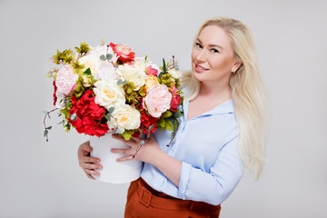 valentine's day or mother's day concept - portrait of beautiful and elegant plus size blonde woman holding box with summer flowers over gray