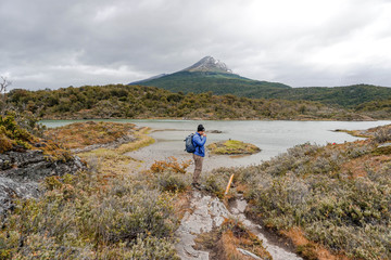 Fototapeta premium Young male with a backpack in Patagonia, Argentina. Hiker hiking rocky mountain surrounding by clouds. Tourism, travelling and healthy lifestyle concept. 
