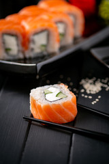 Traditional fresh Japanese Philadelphia sushi rolls on a black wooden background