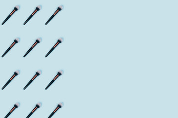 Cosmetic makeup brush on blue color background, top view pattern