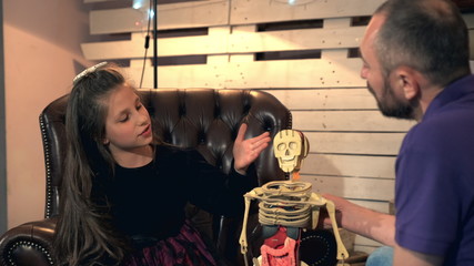 Inquisitive daughter asking her father many questions about human body structure. They are happy to spend free time together at home.