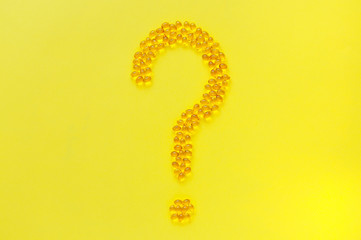 Question mark made of vitamins on a yellow background. Healthcare and medicine concept.
