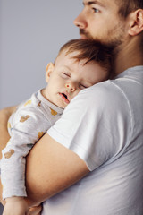 Close up of adorable little boy sleeping deeply and dreaming while his caring father holding him.