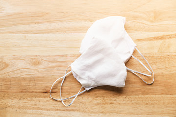 homemade white cloth masks for protection against coronavirus (COVID-19) on wooden table mediumshot