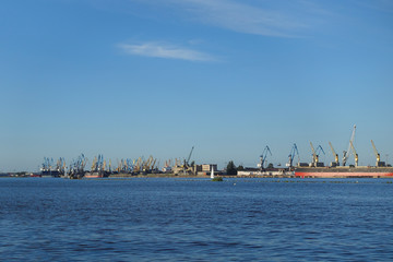 Obraz premium Riga, Latvia, view over the river Daugava to the shoreline with many port cranes