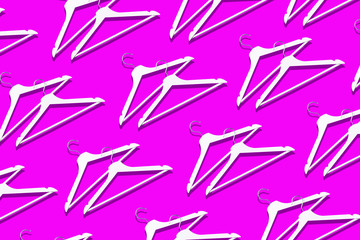 Top view of white clothes hangers on pink background with copy space. Flat lay. Minimalism style and decluttering. Creative layout. Fashion, store sale, shopping concept. Banner for feminine blog