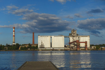 Obraz premium River Daugava and large grain elevators and long chimneys on the opposite bank, Riga, Latvia