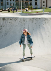 Young woman doing skateboarding trick outdoor during sunny day
