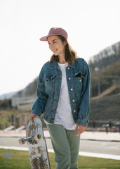 Young woman carrying skateboard looking away outdoor
