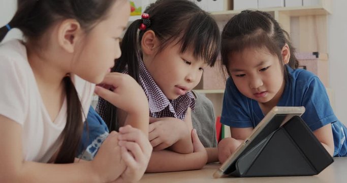 Group of children looking to tablet together. Education, Study, Technology and Lifestyle concept.