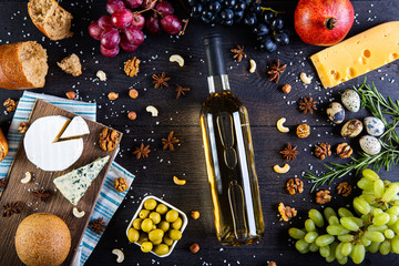 Assortment of cheeses, a bottle of wine, honey, nuts and spices, on a wooden table. Top view. Free space for text.