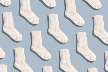 Pair of white woolen knitted socks pattern on grey background. Top view. Copy space. Creative design for packaging. Christmas and New Year cozy holiday composition. Winter weather