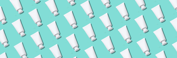 White plastic creams bottles pattern. Cosmetics, skin care, beauty, body treatment concept. Creative design for packaging. Cosmetic jar, tube, bottle on blue background. Top view. Flat lay. Mock-up.