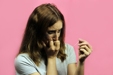 sad saisasiap girl or teenager upset crying, holding pregnancy test on pink background