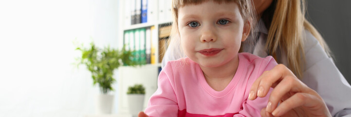 Little baby girl visiting doctor holding in hands red toy heart