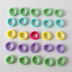 multi-colored elastic bands round for fixing hair pink, yellow, green are arranged in rows on a white surface selective focus