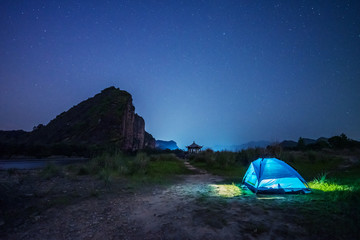
Tourist hikers tent in mountains at night with stars in the sky 