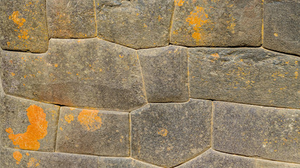 inca stone wall with perfect shaped granite and fitting stones, orange fields covered gray peruvian stones from ancient architecture pattern