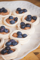 A very tender delicious pastry custard nest with blueberries on a white dish. Fresh organic meringues for the holiday.