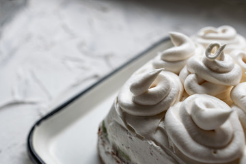 Cream dessert of airy Italian meringue. Whipped egg whites with hot sugar syrup. Light delicate cake cream in the form of a twisted peak on the top of the head in a spiral