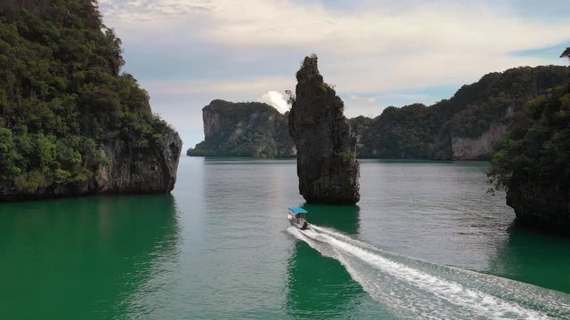 Drone pushing forwards following a speed boart departing from a secret bay at Pang Na Bay near Koh Yao Noi island in Thailand.