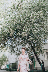 a girl with short blond hair walks around the city in a raincoat blooming in spring