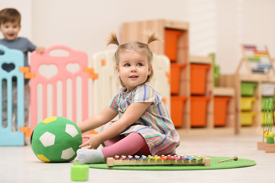 Cute Little Child Playing With Soft Ball On Floor At Home