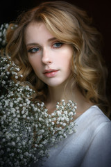 sad beautiful blonde with flowers indoors