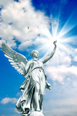 angel archangel with rays of divine light over beautiful blue cloudy sky 