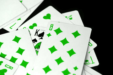 Playing cards unusual green color scattered on a black surface close-up. Gambling background