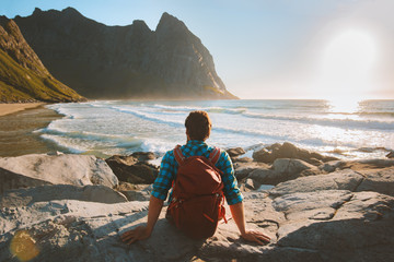 Man sitting on Kvalvika beach enjoying ocean view travel vacations eco tourism outdoor backpacking in Norway healthy lifestyle summer trip