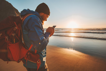 Man traveling with backpack using smartphone on beach navigation application modern technology...