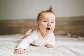 Cute baby infant crawling at home curious child portrait family lifestyle 3 month old girl kid - obrazy, fototapety, plakaty