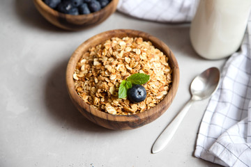 Top view on a wooden bowl with freshly prepared granola or oatmeal granola with blueberries, a glass of milk nearby. Healthy breakfast at home for children