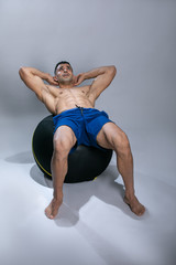 Fototapeta na wymiar Attractive young man using exercise ball. Attractive young man exercising abs .