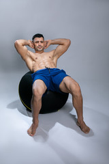 Attractive young man using exercise ball. Attractive young man exercising abs .
