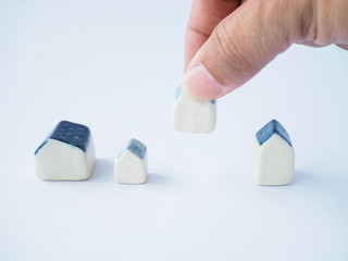 The hand is picking up a small ceramic house to arrange. The management of the concert, with space to put text.