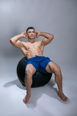 Obraz premium Attractive young man using exercise ball. Attractive young man exercising abs .