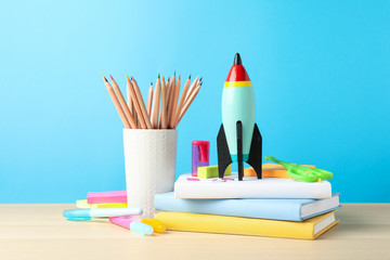 Obraz premium Bright toy rocket and school supplies on wooden table