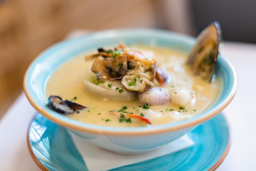 Seafood soup close-up. East Asian cuisine. A plate of seafood soup. A man with a spoon stirs squid oysters squid lobster shells.
