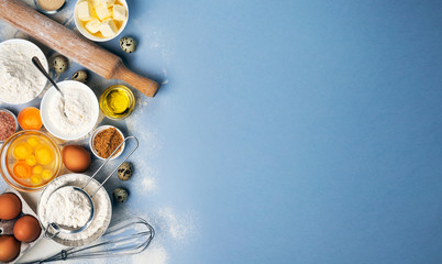 Fototapeta na wymiar Baking ingredients on blue color background, top view