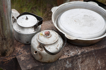 Close-up of aluminium kettles and a closed basin. Field kitchen.