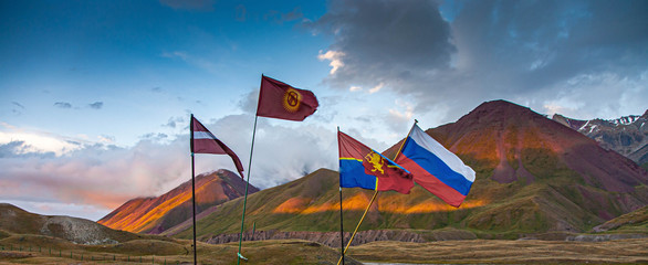 Beautiful nature. Scenic landscape of mountain peaks. Waving flags of Latvia, Russia, Kyrgyzstan.