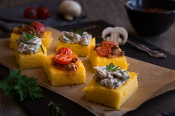 Slices of fried polenta with mushrooms and tomato sauce