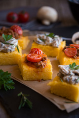 Slices of fried polenta with mushrooms and tomato sauce