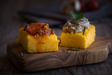 Slices of fried polenta with mushrooms and tomato sauce