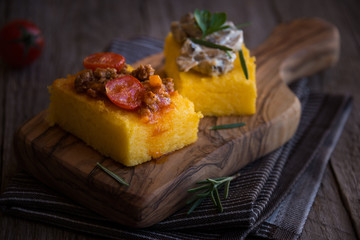 Slices of fried polenta with mushrooms and tomato sauce