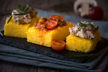 Slices of fried polenta with mushrooms and tomato sauce