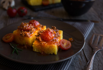 Slices of fried polenta with meat and tomato sauce