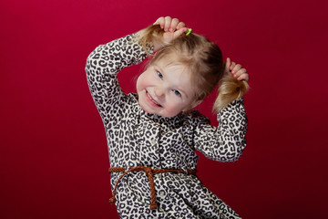 little girl plays and laughs, holds pens on her tails and smiles